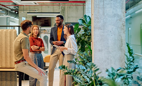 group of five professionals engaged in discussion in a modern office environment with greenery and collaborative workspace features 6 strategies for teamwork and communication