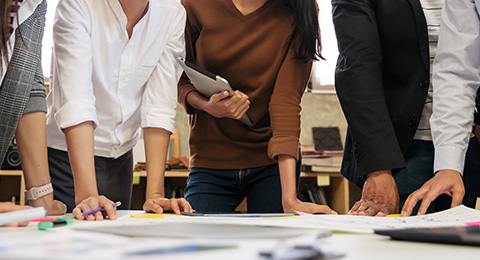 Group of people collaborating on a project at a table with documents and stationery involved in brainstorming and discussion related to teamwork and planning strategies 4 diverse ideas