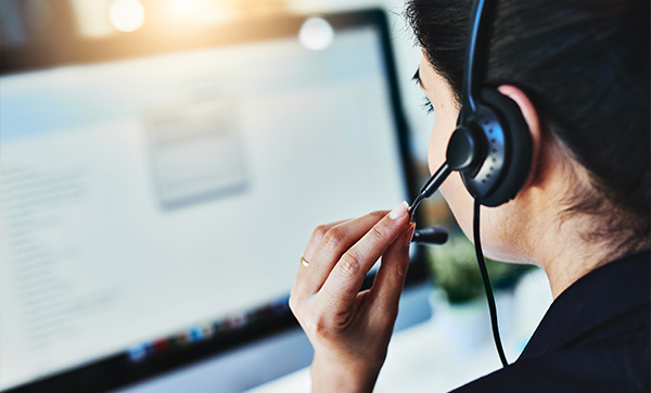 woman with headset in front of computer screen during a work call in a busy office with seven key communication points
