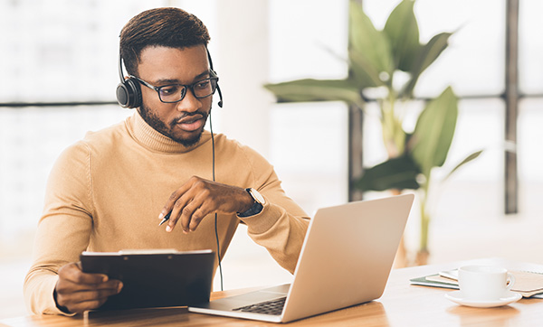 a man wearing headphones studying with a laptop and taking notes in a bright indoor environment modern study techniques for effective learning and productivity