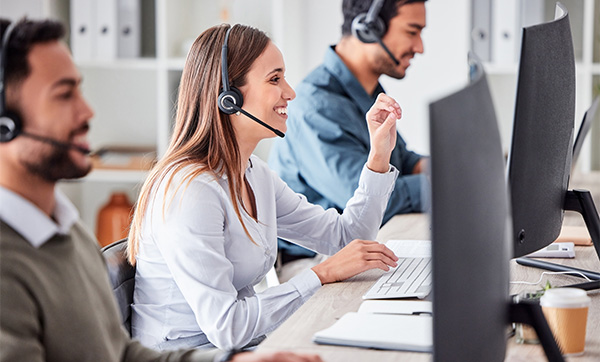 three customer service representatives engaged in a call center setting using computers and headsets six communication skills focused teamwork