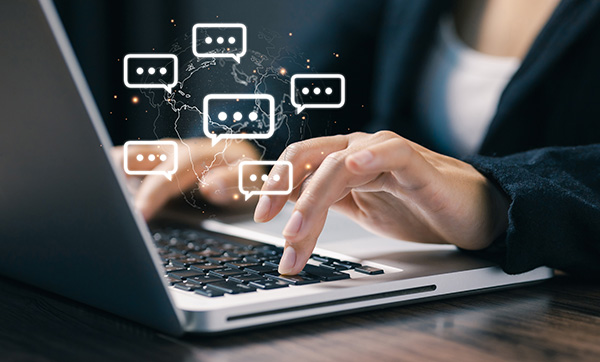 a person typing on a laptop with floating chat bubbles and a world map representing digital communication and engagement for effective interactions in five key areas