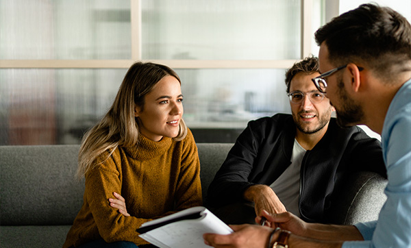 three people engaged in discussion while sitting on a couch in a modern office setting sharing ideas and collaborating effectively 4 teamwork concepts
