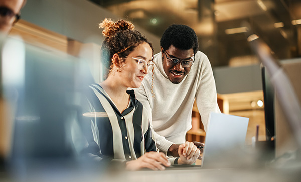 two colleagues collaborating on a laptop in a modern office setting discussing strategies to enhance project outcomes and productivity through teamwork 6 ideas