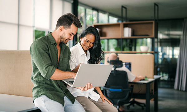 two people smiling while using a laptop in a modern workspace focused on teamwork and collaboration with five innovative ideas