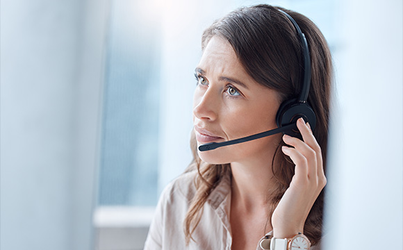woman in a headset looking thoughtful at work in a modern office environment providing customer service support