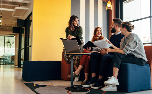 four people collaborating in a modern office space discussing ideas and working on projects with laptops and documents creating a productive atmosphere for teamwork and interaction 2 professionals 2 ideas