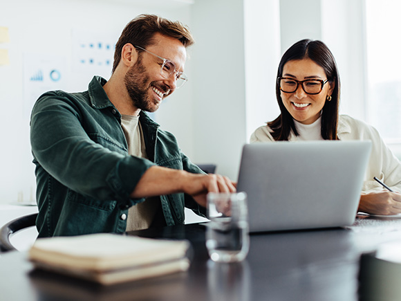 two colleagues collaborating on a laptop sharing ideas in a modern office environment focused on teamwork and productivity in a workspace