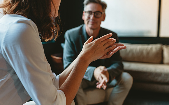 professional discussion between two people with one person gesturing and the other listening attentively in a cozy setting