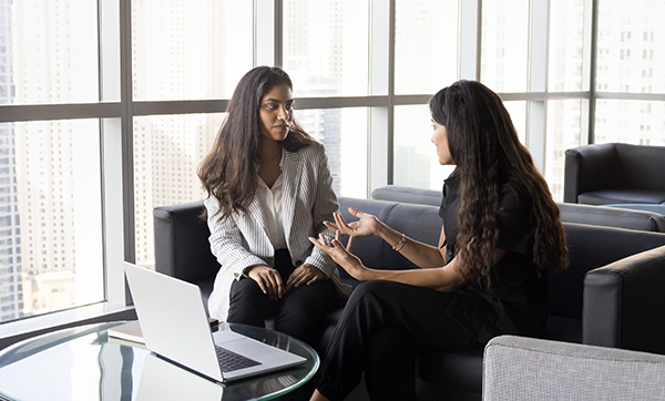 two women having a discussion in a modern office with a laptop on a table 4 ways to collaborate effectively